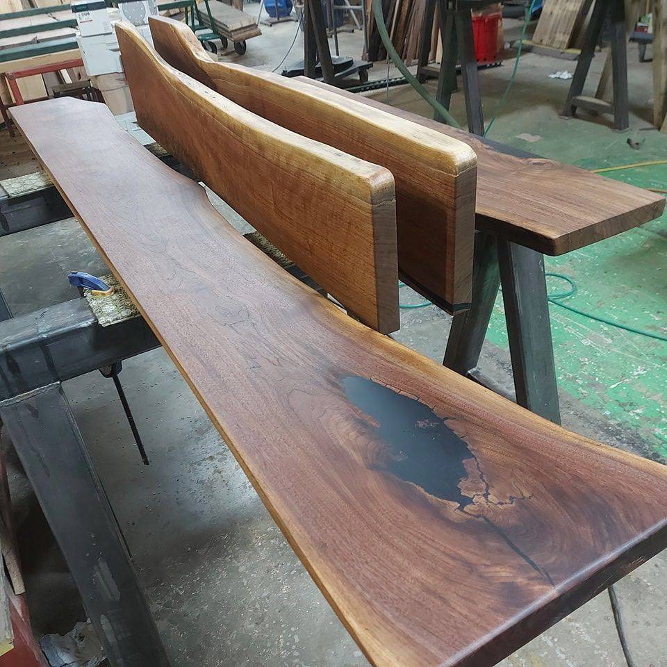 Black walnut slabs on sawhorses in the shop, one with a filled void, waiting on finish